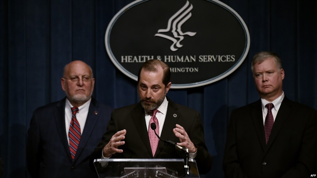 Human Services Secretary Alex Azar speaks as Centers for Disease Control and Prevention (CDC) director, Robert R. Redfield, left, and Deputy Secretary of State Stephen Biegun listen during a press conference, Feb. 7, 2020 in Washington.