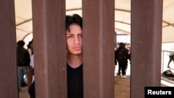 ARCHIVO - El migrante peruano Angelo Cardosa mira a través del muro fronterizo entre México y Estados Unidos en San Luis Río Colorado, en México, antes del levantamiento del Título 42, visto desde San Luis, Arizona, Estados Unidos, el 11 de mayo de 2023.