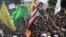 Muslims burn an American flag following a protest over an anti-Islam video that denigrates the Prophet Muhammad, in Kaduna, Nigeria, September 24, 2012. On the walls behind the protesters it reads: 'Death to the Americans, Death to the Israelites.