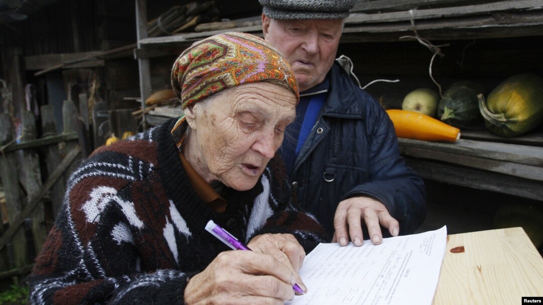 Belaruslik ayol saylov varaqasini to'ldirmoqda. 23-sentabr, 2012-yil.