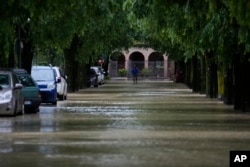 FILE - A man walks in the flooded village of Castel Bolognese, Italy, Wednesday, May 17, 2023. Exceptional rains Wednesday in a drought-struck region of northern Italy swelled rivers over their banks, killing at least eight people, forcing the evacuation of thousands and prompting officials to warn that Italy needs a national plan to combat climate change-induced flooding. (AP Photo/Luca Bruno)