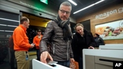 A customer scans his Amazon Go cellphone app at the entrance as he heads into an Amazon Go store, Jan. 22, 2018, in Seattle.