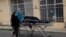 A healthcare worker in protective gear pushes the body of a man to the spot where his family will wait for a funeral home to take him away, outside the General Hospital in La Paz, Bolivia, July 23, 2020. 