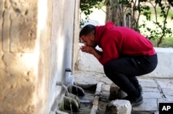 A man drinks water from a water source in Sidi Bou Said, north of Tunis, on April 12, 2023. (AP Photo/Hassene Dridi)