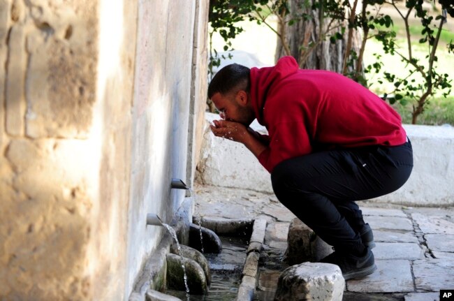 A man drinks water from a water source in Sidi Bou Said, north of Tunis, on April 12, 2023. (AP Photo/Hassene Dridi)