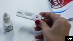 FILE - A woman demonstrates how an HIV self-test kit works, in Rio de Janeiro, Brazil, July 07, 2017.