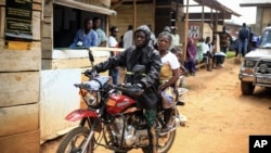 FILE - Motorcycle taxi driver Germain Kalubenge transports a woman whose 5-year-old daughter had a fever and was vomiting to an Ebola transit center where potential cases are evaluated, in Beni, Congo, Aug. 22, 2019. 