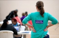 FILE - A poll watcher watches as voters sign in at the Martha O'Bryan Center community building in Nashville, Tenn., Nov. 8, 2016.