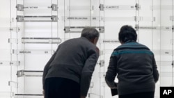 Children of former Associated Press journalist Y.C. Jao, Rao Jian, left, and his younger sister Rao Jiping, right, bow after unveiling their father's name on the memorial Wall of Honor at the AP headquarters in New York, Dec. 11, 2019. 