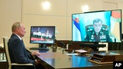 File- Russian President Vladimir Putin listens to General Staff chief Valery Gerasimov, on the screen, during a video conference reporting a successful test launch of the new Zircon hypersonic cruise missile, Oct. 7, 2020.