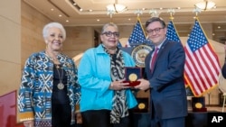 El presidente de la Cámara de Representantes, Mike Johnson entrega póstumamente una Medalla de Oro del Congreso a Joylette Hylick y Katherine Moore, hijas de matemática negra de la NASA Katherine Johnson, en el Capitolio en Washington, el 18 de septiembre de 2024.