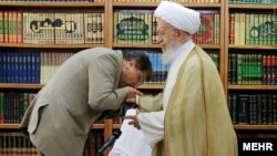 بوسه علی جنتی بر دست مکارم شیرازی. او چندین بار با مراجع تقلید دیدار کرد