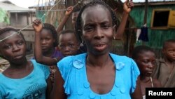 A woman poses for a photograph with her children in front of house in the slum of Makoko in Lagos, Nigeria, January 22, 2013