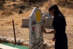 FILE - Layla Taloo visits the grave of a Yazidi woman who took her own life after she was captured by Islamic State militants in Mosul, buried on a hill overlooking the Lalish shrine in northern Iraq, Sept. 13, 2019.