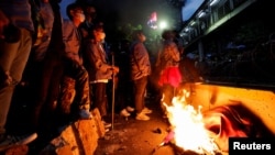 Beberapa demonstran berdiri di dekat barikade yang terbakar selama aksi protes terhadap kenaikan harga BBM di luar kompleks Monumen Nasional di Jakarta, Selasa malam 13 September 2022.