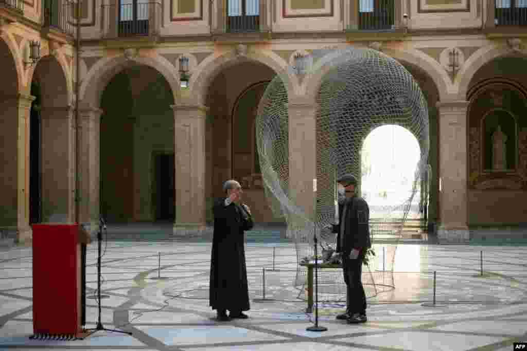 Un sacerdote revisa un micrófono con un técnico de sonido en la abadía de Santa María de Montserrat el 5 de abril de 2020, antes de la celebración de la misa del Domingo de Ramos en Monistrol de Montserrat. España vio este domingo su tercer descenso diario consecutivo en el número de personas que mueren por la pandemia de coronavirus.