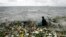 File - A man collects recyclable plastic materials, washed ashore by waves in Manila.