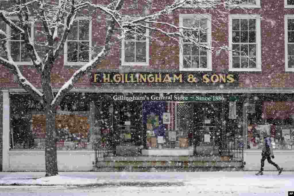 A pedestrian walks by a store during a Thanksgiving Day snowstorm on Nov. 28, 2024, in Woodstock, Vermont.