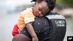 Un migrante haitiano sostiene a su hijo antes de abordar un bote hacia Capurganá, cerca de la frontera con Panamá, el miércoles 28 de julio de 2021, en Necoclí, Colombia. [AP Foto/Iván Valencia]