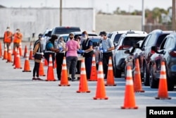Florida Department of Health medical workers prepare to administer a COVID-19 vaccine to seniors in the parking lot of the Gulf View Square Mall in New Port Richey near Tampa, Florida, Dec. 31, 2020.