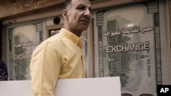 FILE - An Egyptian man walks past a currency exchange office in Cairo, Egypt, on March 6, 2024. The International Monetary Fund announced on March 29 that it had confirmed a deal to increase Egypt's bailout loan from $3 billion to $8 billion.