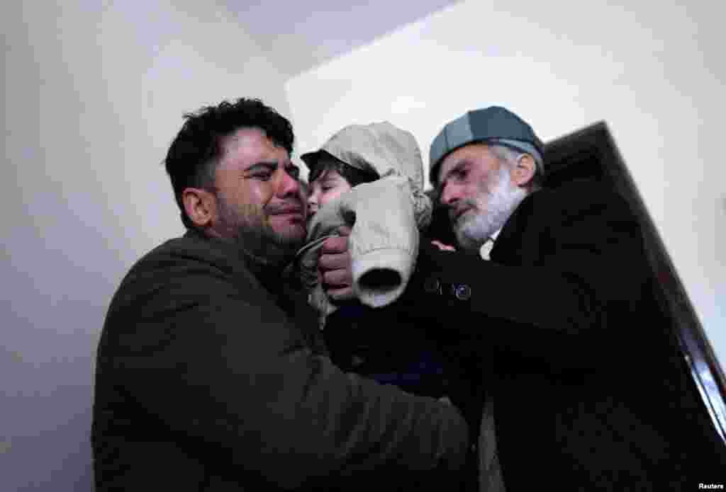 Hamid Safi, a 29-year-old taxi driver who had found baby Sohail Ahmadi in the airport, cries as he hands over Sohail to his grandfather Mohammad Qasem Razawi in Kabul, Afghanistan, Jan. 8, 2022.