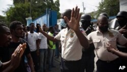 La gente presiona a la policía para que entregue a dos hombres que fueron arrestados y los cuerpos de dos hombres asesinados por la policía, con el fin de quemarlos en represalia por el asesinato del presidente, Puerto Príncipe, el 8 de julio de 2021.