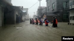 Rescue workers walk on a flooded street at a town hit by Typhoon Soudelor in Ningde, Fujian province, China, Aug. 9, 2015. 