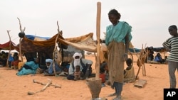 FILE - A woman prepares a meal at a Malian refugee camp in Chinegodar, western Niger, close to the Malian border, February 4, 2012.