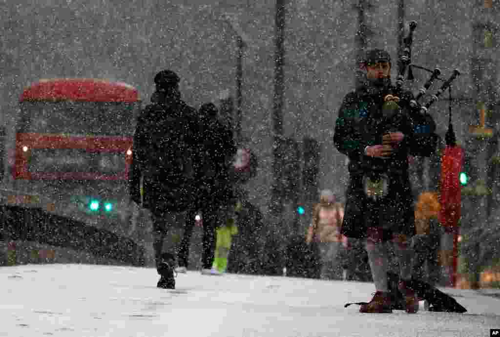 눈이 내리는 영국 런던의 웨스트민스터 다리에서 한 남자가 백파이프를 연주하고 있다. 