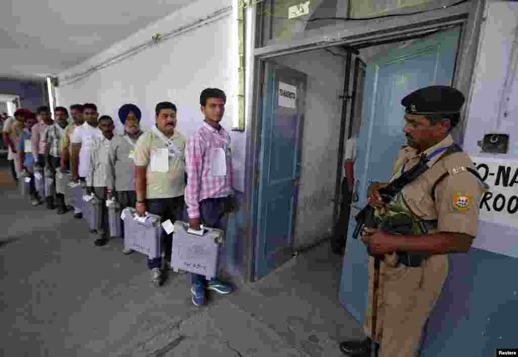 A policeman stands guard as polling officials carrying electronic voting machines arrive to count votes, in Jammu, May 16, 2014.