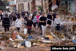 Residents walk in a street after flooding in Paiporta, near Valencia, Spain, Wednesday, Oct. 30, 2024. (AP Photo/Alberto Saiz)