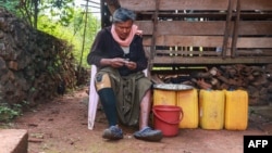 This photo taken on November 18, 2024 shows Myanmar farmer Hla Han, 52, who lost his leg after stepping on a mine, peeling garlic outside his house in Demoso township, eastern Kayah state.