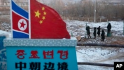 FILE - A Chinese-built fence near a concrete marker depicting the North Korean and Chinese national flags with the words "China North Korea Border" at a crossing in the Chinese border town of Tumen in eastern China's Jilin province. 