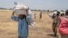 South Sudanese men carry food distributed by the World Food Program in Leer County Southern Leich State in South Sudan, March 6, 2017.