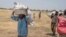 South Sudanese men carry food distributed by the World Food Program in Leer County Southern Leich State in South Sudan, March 6, 2017.