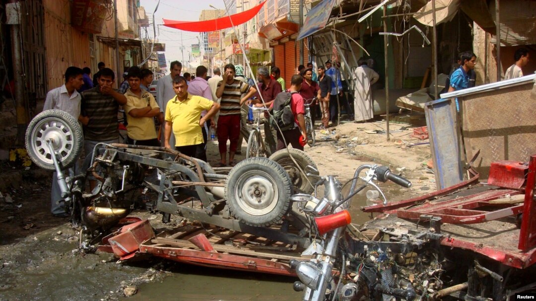Warga di Diwaniya, selatan Baghdad, melihat lokasi serangan bom di pasar setempat yang menewaskan sedikitnya 25 orang (3/7). 