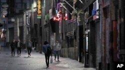 People walk past closed bars as new measures across the region are set to come into force in Liverpool, England, Wednesday, Oct. 14, 2020. 