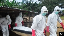 Tim pemakaman mengenakan pakaian pengaman membawa mayat seorang perempuan yang dicurigai meninggal akibat virus Ebola di Monrovia, Liberia. 18 Oktober 2014. 