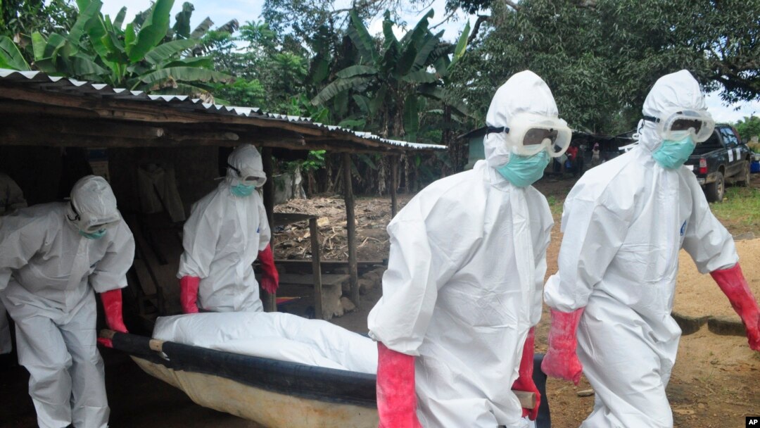Tim pemakaman mengenakan pakaian pengaman membawa mayat seorang perempuan yang dicurigai meninggal akibat virus Ebola di Monrovia, Liberia. 18 Oktober 2014. 