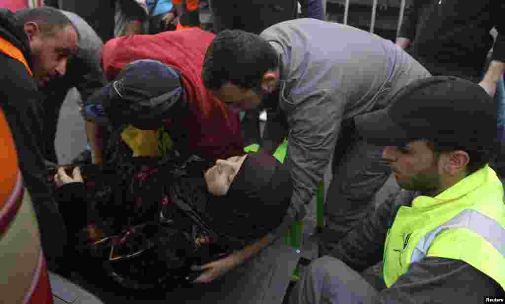 Civil Defense personnel help a woman at the scene of a bomb blast in Haret Hreik, Beirut, Jan. 21, 2014.