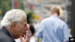 A man looks into a store window as he smokes in the street in New York (File)