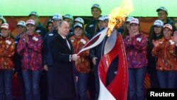 Russian President Vladimir Putin holds a lighted Olympic torch during a ceremony to mark the start of the Sochi 2014 Winter Olympic torch relay in Moscow, Oct. 6, 2013.