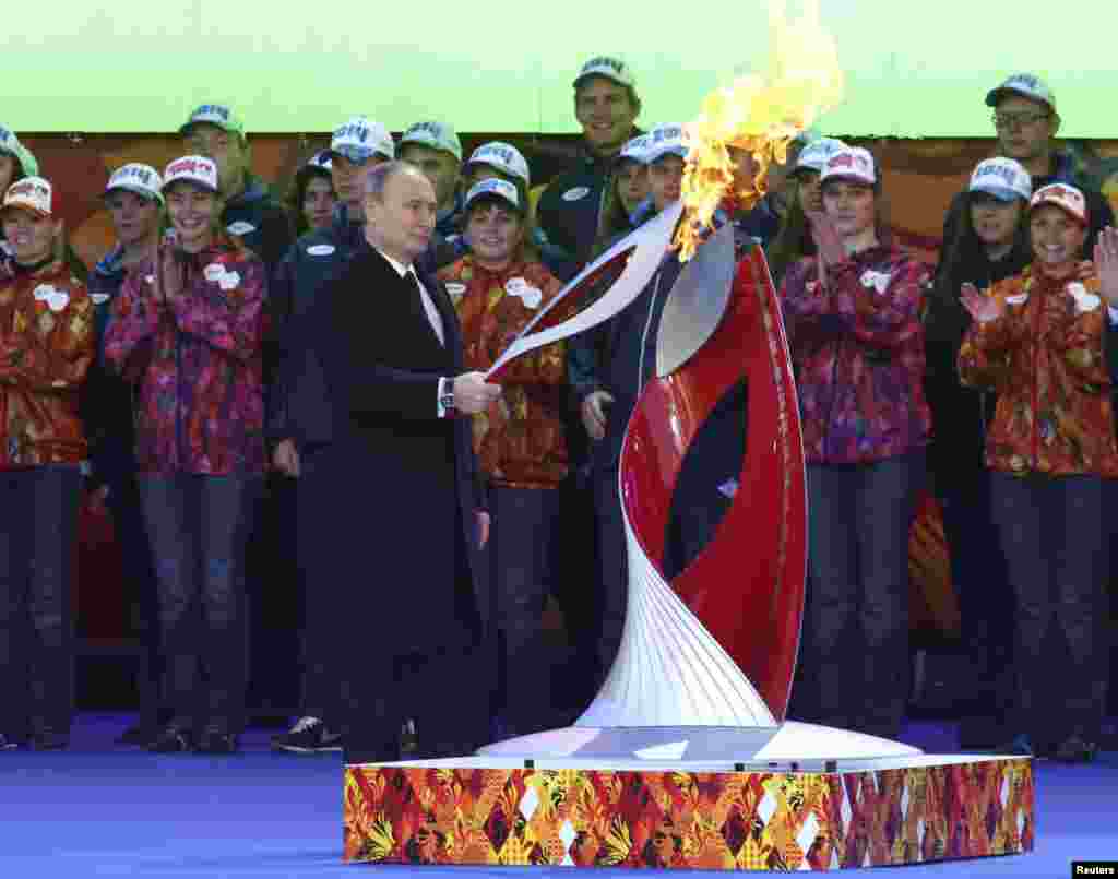 Russian President Vladimir Putin holds a lighted Olympic torch during a ceremony to mark the start of the Sochi 2014 Winter Olympic torch relay, Moscow, Oct. 6, 2013.