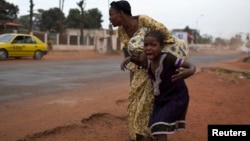 A mother holds her child while attempting to take cover as repeated gun shots are heard close to Miskine district during continuing sectarian violence in the capital Bangui, Central African Republic, Jan. 28, 2014.