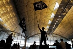 Anti-extradition bill protesters wave flags with Chinese calligraphy that reads "Liberate Hong Kong, the revolution of our times," at a mass demonstration at Hong Kong International Airport, in Hong Kong, China, Aug. 12, 2019.