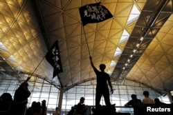 Anti-extradition bill protesters wave flags with Chinese calligraphy that reads "Liberate Hong Kong, the revolution of our times," at a mass demonstration at Hong Kong International Airport, in Hong Kong, China, Aug. 12, 2019.