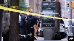 An investigator picks up a suspicious package that was thought to be an explosive device in Manhattan's Chelsea neighborhood Friday, Aug. 16, 2019, in New York. The appliance was deemed harmless and taken away as evidence.