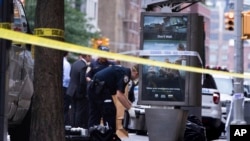 An investigator picks up a suspicious package that was thought to be an explosive device in Manhattan's Chelsea neighborhood Friday, Aug. 16, 2019, in New York. The appliance was deemed harmless and taken away as evidence.