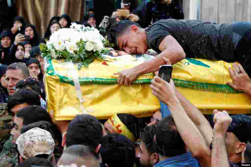 A man reacts while clenching onto the coffin of Hezbollah fighter Jalal al-Effie, who was killed during clashes in Syria's Aleppo, during his funeral in Beirut's southern suburbs, Lebanon.